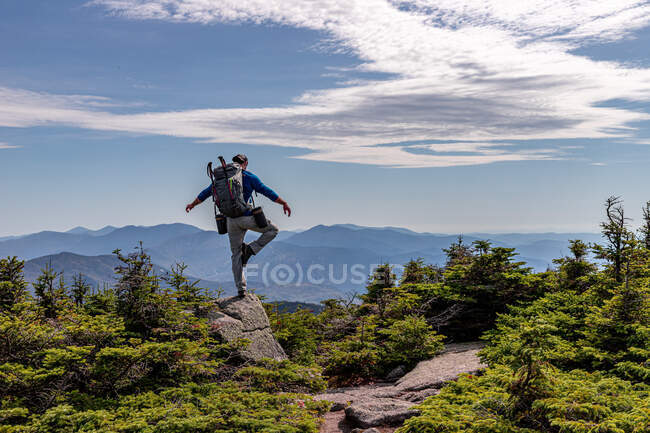 Randonneur avec sac à dos debout sur le sommet de la montagne en arrière-plan — Photo de stock