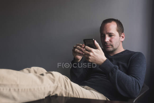 Homme détendu vérifiant son smartphone à la maison — Photo de stock