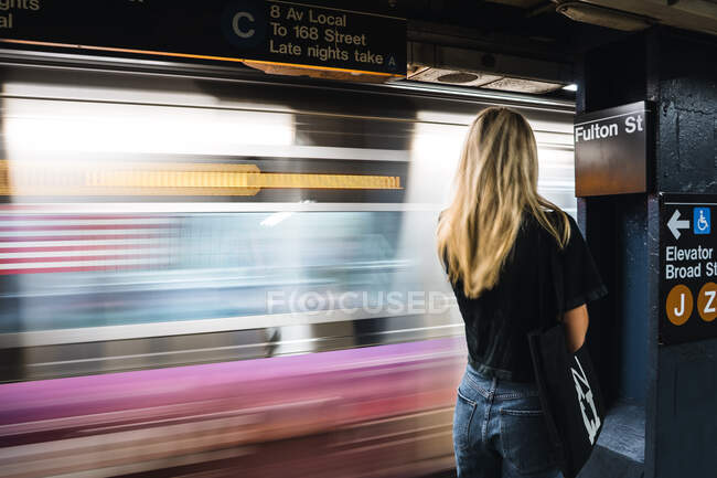 Menina bonita esperando na estação de metro com movimento de trem — Fotografia de Stock