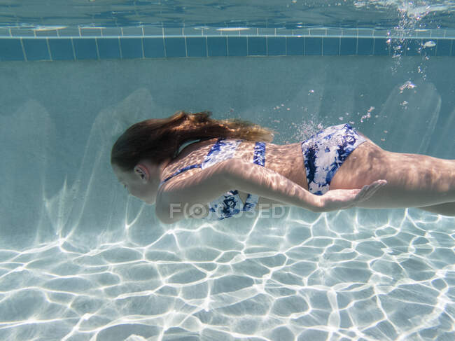 Tween chica nadando bajo el agua en piscina en Indialantic, FL - foto de stock