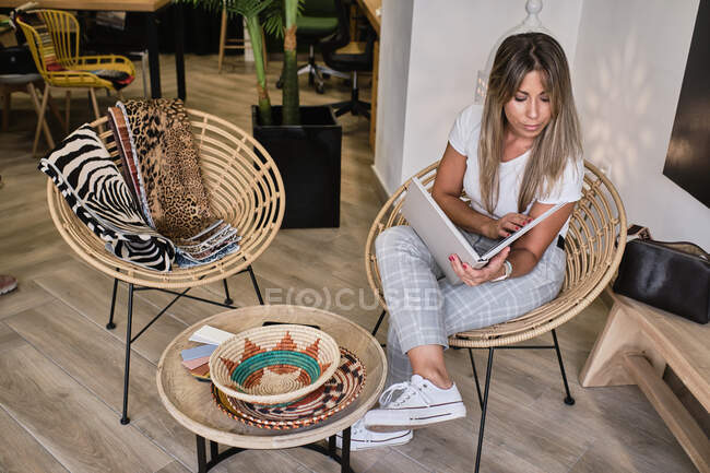 Young girl looks at resource book while waiting for cloth salesman — Stock Photo