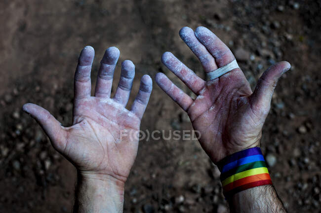 Look at the hands and fingers of a climber with the gay pride bracelet. — Stock Photo