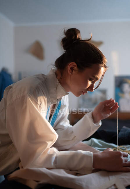 Side view of home business owner sewing fabrics while creating new handcrafted clothing — Stock Photo
