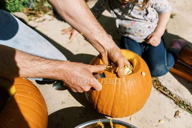 Little girl carving out pumpkins for halloween with her dad — Stock Photo