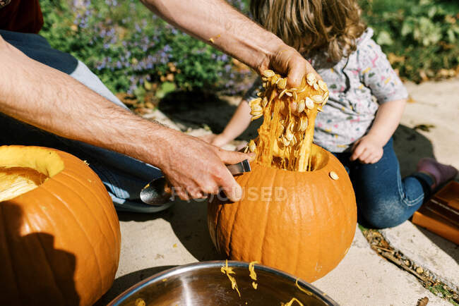 Petite fille sculptant des citrouilles pour Halloween avec son père — Photo de stock