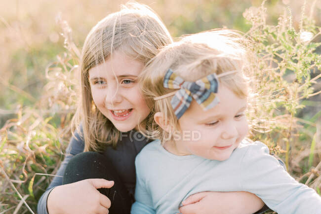 Deux sœurs souriant ensemble par une journée venteuse dehors — Photo de stock