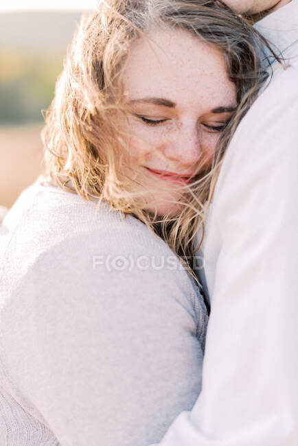 A beautiful woman being held by her husband on a windy day — Stock Photo