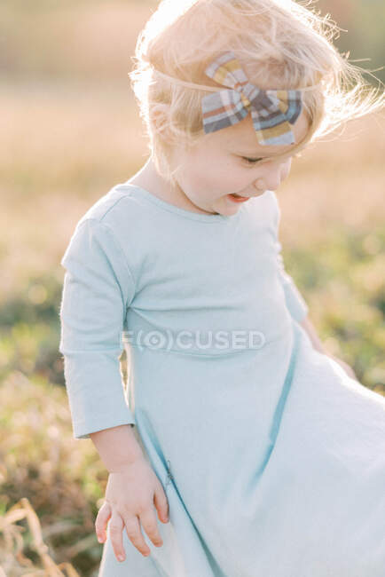 A toddler girl watching her dress fly in the wind — Stock Photo