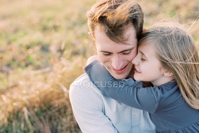 Une fille heureuse et aimante de cinq ans s'accrochant à son père — Photo de stock