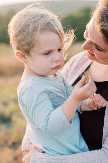 Una bambina felice e amorevole tenuta in braccio dalla madre in una giornata ventosa — Foto stock