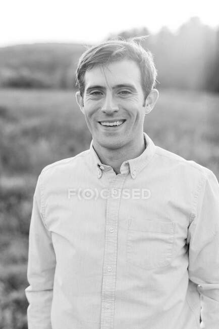 Um jovem de pé na grama e sorrindo — Fotografia de Stock