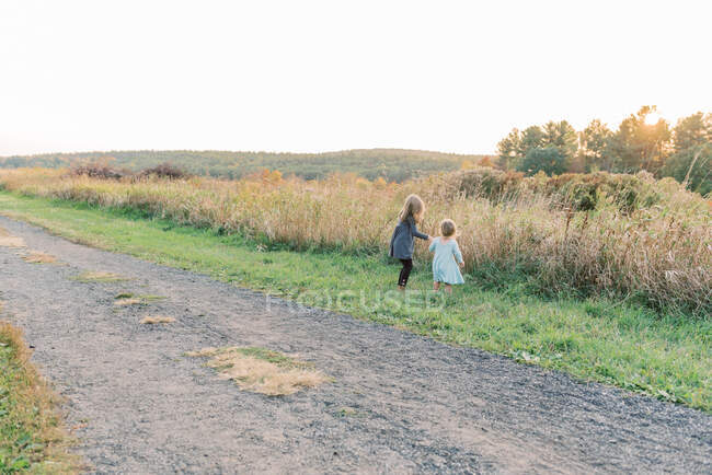 Dos chicas en vestidos explorando la madre naturaleza durante el atardecer - foto de stock