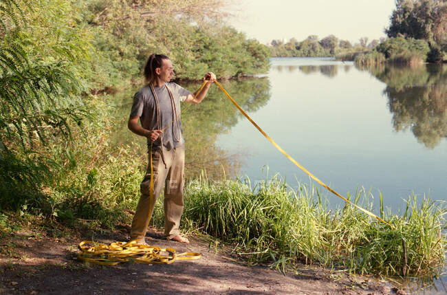 Un hombre practicando slackline sobre un río en el bosque al atardecer - foto de stock