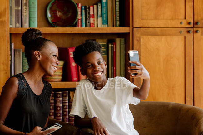Maman noire posant pour selfie avec un fils souriant pendant ses études à la maison — Photo de stock