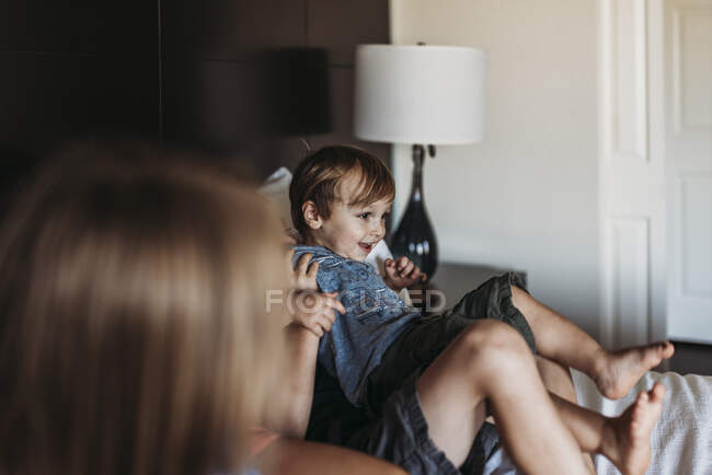 Young toddler boy laughing on hotel bed on vacation in Palm Springs — Stock Photo