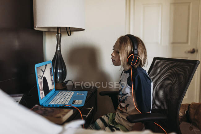 School age boy distance learning in hotel room during pandemic — Stock Photo