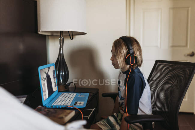 School age boy distance learning in hotel room during pandemic — Stock Photo