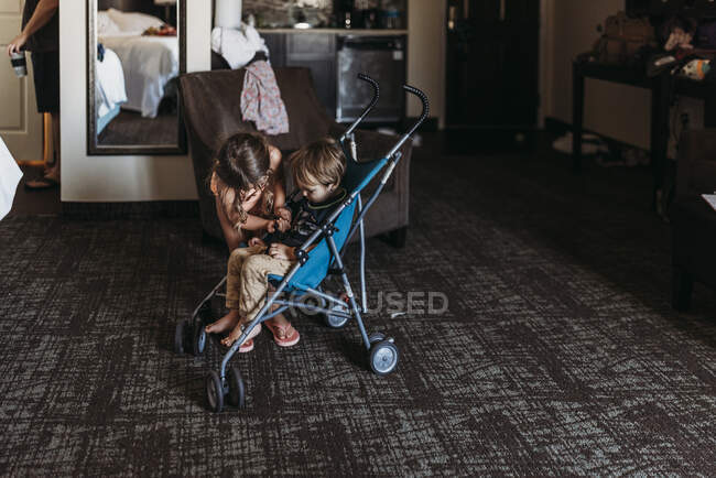 Hermanitos jugando en cochecito en habitación de hotel en Palm Springs - foto de stock