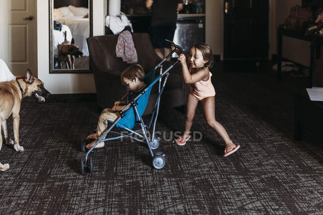 Jeunes frères et sœurs jouant en poussette dans une chambre d'hôtel à Palm Springs — Photo de stock