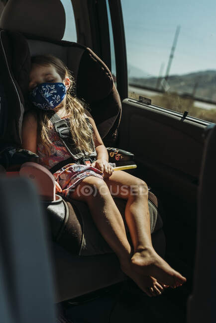Молода дошкільна дівчинка з масками на підвіконні в машині. — стокове фото