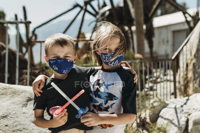 Close up portrait of young brothers with masks on outside on vacation — Stock Photo