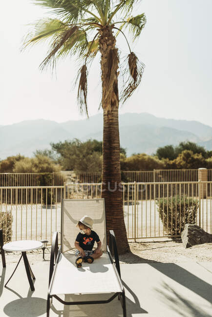 Jovem criança com uma máscara sentada à beira da piscina em Palm Springs — Fotografia de Stock