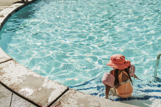 Behind view of little girl swimming in pool on vacation Palm Springs — Stock Photo