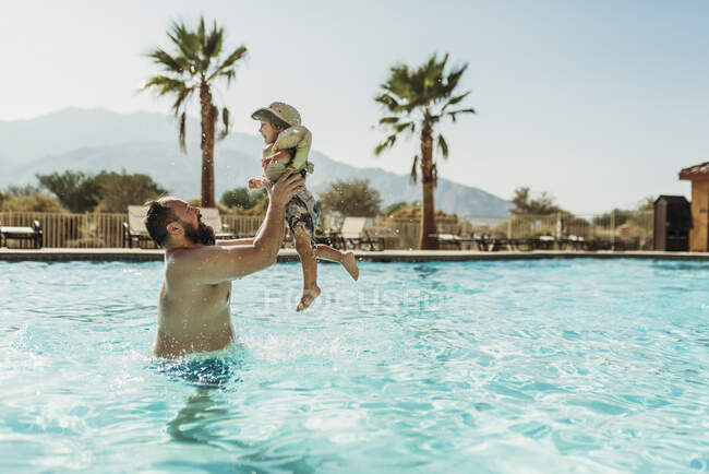 Padre jugando con su hijo en la piscina - foto de stock