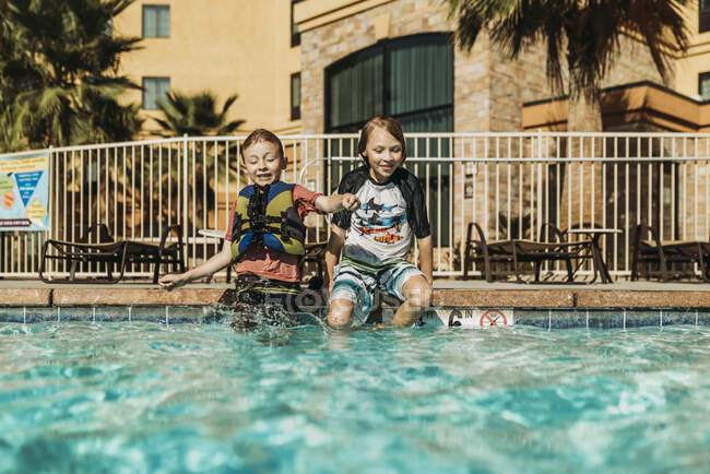 Young brothers jumping into pool together on vacation in Palm Springs — Stock Photo