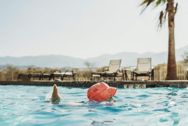 Vista de ângulo lateral da menina em chapéu rosa nadando na piscina — Fotografia de Stock