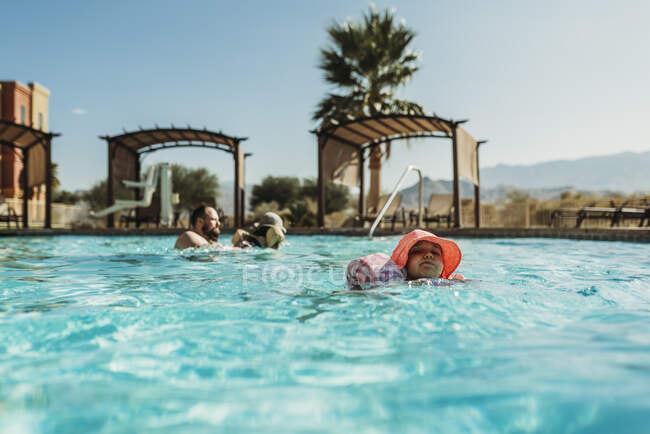 Niña en edad preescolar joven nadando en la piscina de vacaciones en Palm Springs - foto de stock