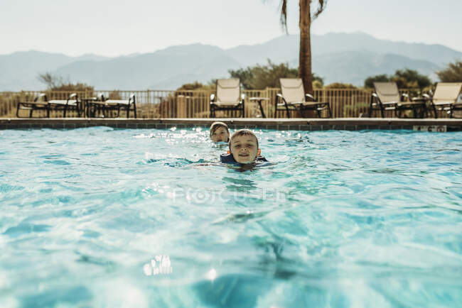 Hermanos jóvenes nadando en una gran piscina en California de vacaciones - foto de stock