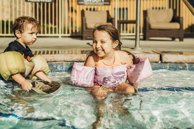 Vista frontal de jovens irmãos brincando na piscina de férias na Califórnia — Fotografia de Stock