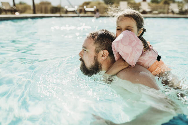 Pai e filha nadando juntos em uma piscina em férias na Califórnia — Fotografia de Stock