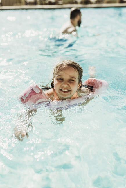Lifestyle portrait of young girl swimming in hotel pool on vacation — Stock Photo