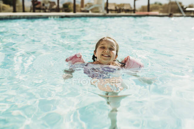 Lifestyle portrait of young girl swimming in hotel pool on vacation — Stock Photo