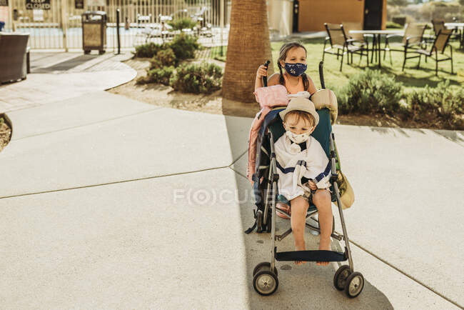 Young children in stroller leaving pool with masks on vacation — Stock Photo