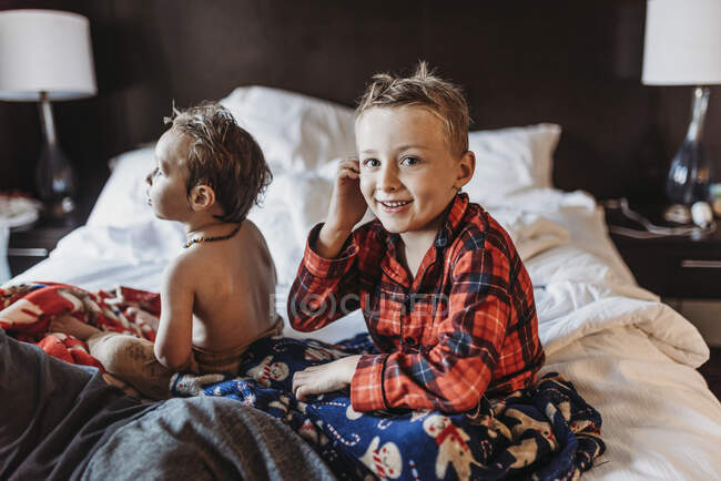 Young boy in pajamas sitting on hotel bed on vacation — Stock Photo