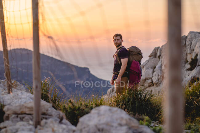 Voyageur solitaire se tient sur un point de vue d'une montagne pendant le coucher du soleil — Photo de stock