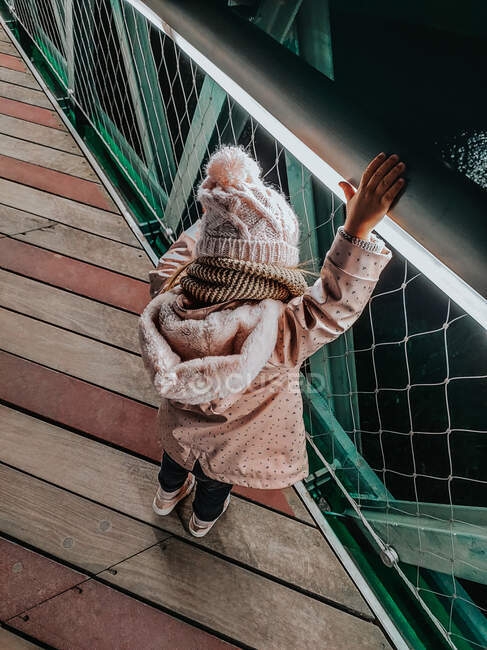 Bambina che indossa un cappello rosa giocando su una ringhiera ponte di notte — Foto stock