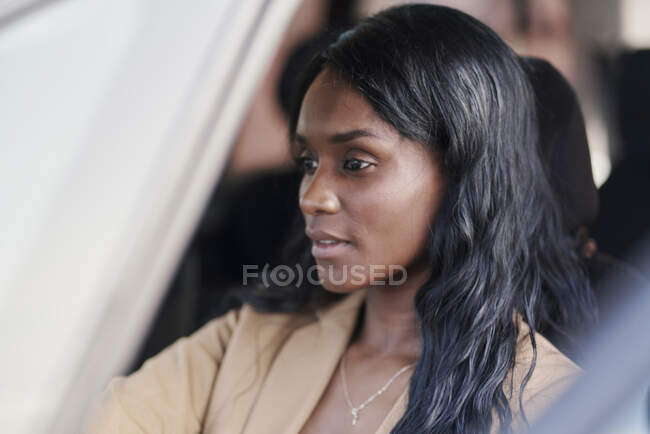Retrato de mulher negra usando um terno marrom dirigindo um carro. conceito de negócio — Fotografia de Stock