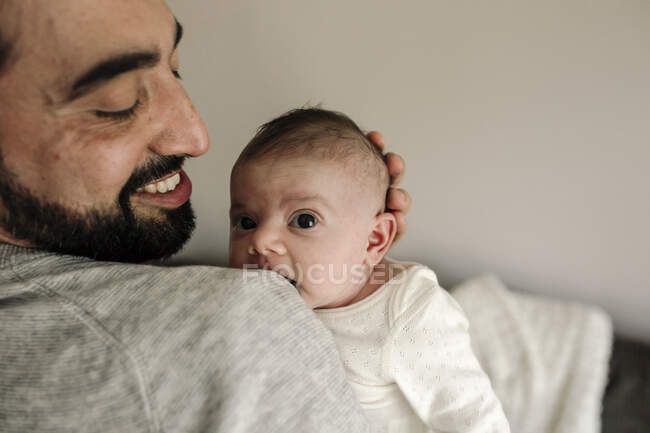 Joyeux papa avec barbe et beau sourire tenant bébé nouveau-né — Photo de stock