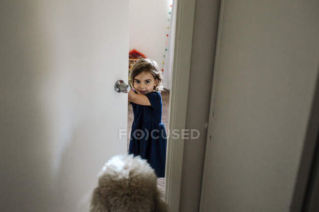 4 anos de idade menina olhando para fora através da porta do quarto — Fotografia de Stock