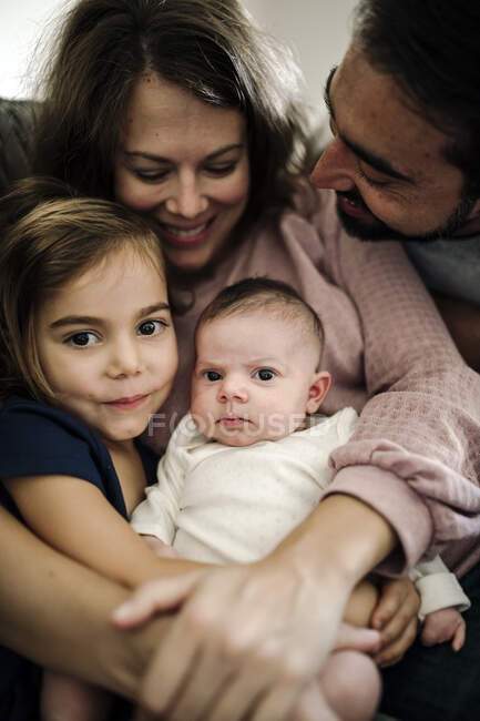 Mamma e papà con barba abbracciare neonato e giovane figlia — Foto stock