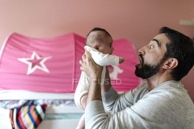 Dad with beard making faces at infant daughter — Stock Photo