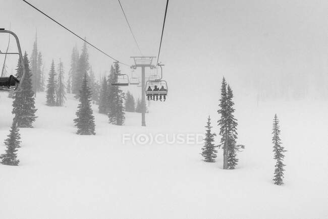 Skiers on chairlift in blizzard — Stock Photo
