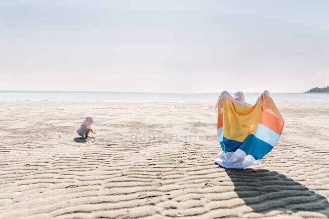 Crianças na praia com toalha colorida brilhante — Fotografia de Stock