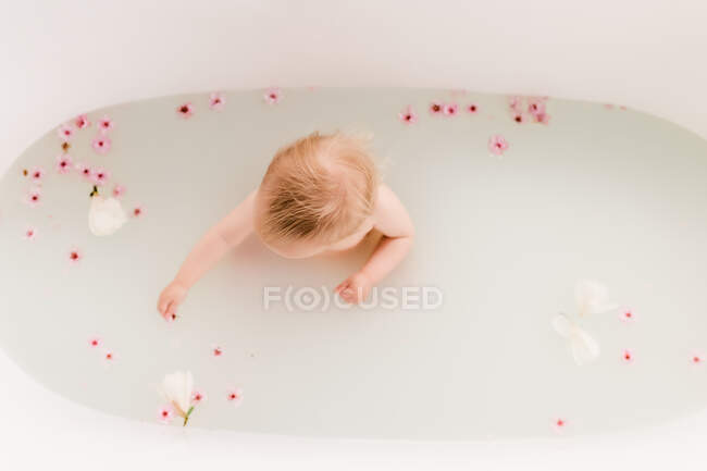 Bebé en un baño de flores con flores de cerezo - foto de stock