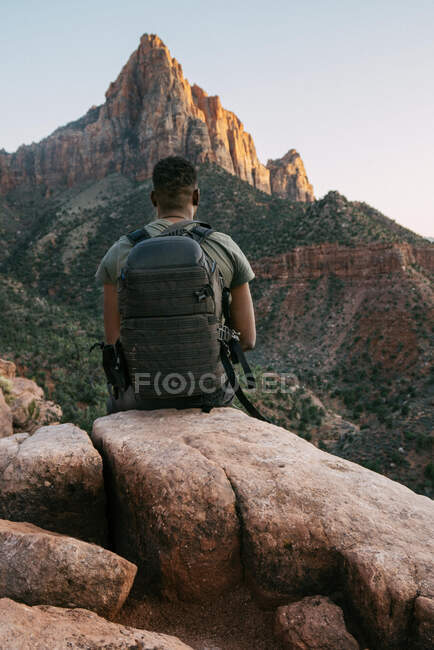 Homem contemplando o pico da montanha de Sião enquanto sentado em uma rocha — Fotografia de Stock