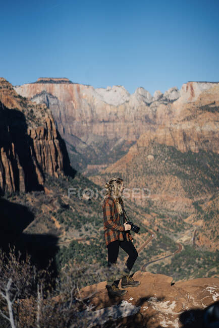 Chica joven posando con una cámara con el Parque Nacional Zion como fondo - foto de stock